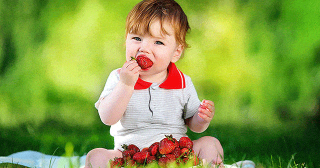 Un bébé qui mange des fraises